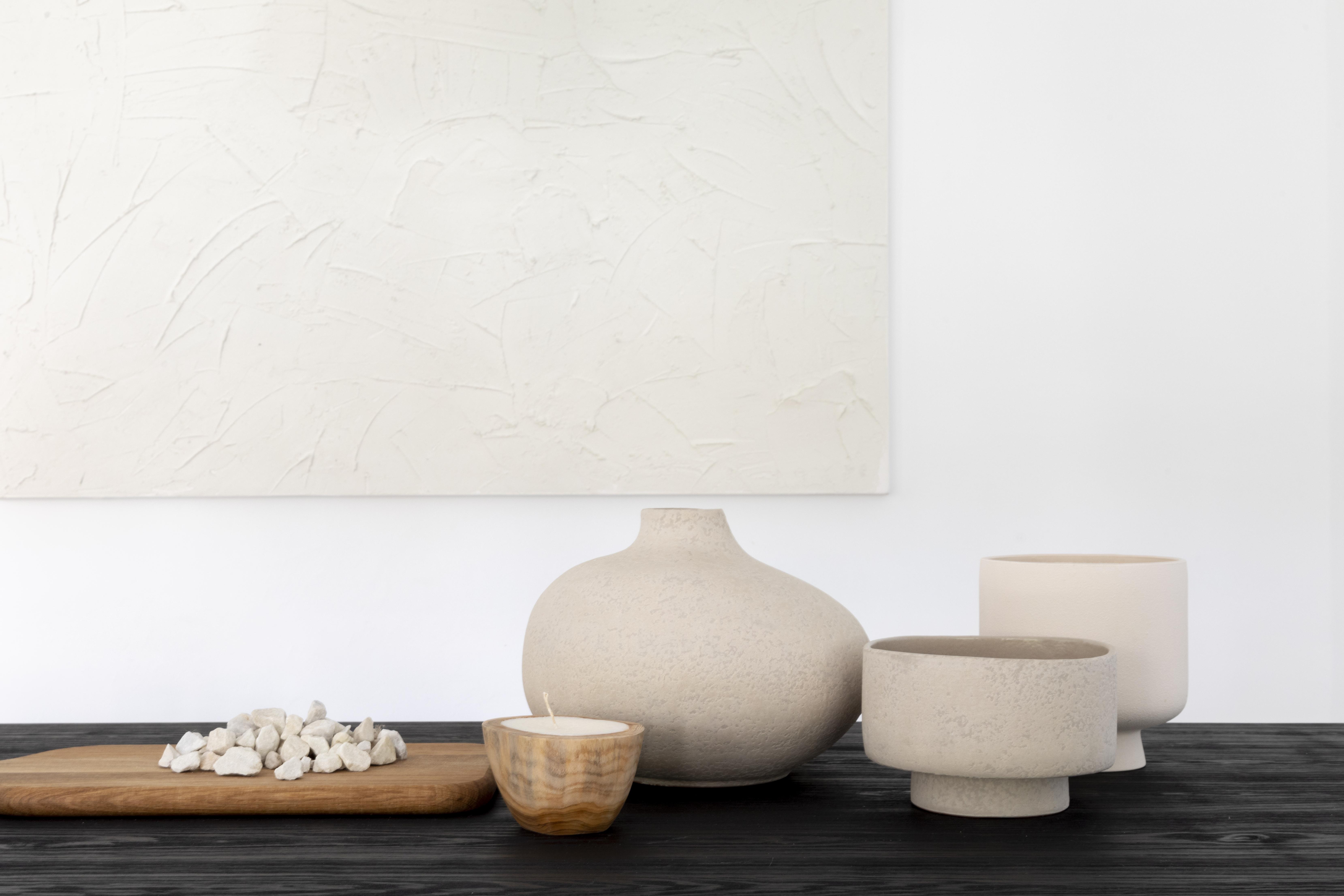 Composición decorativa minimalista con cerámicas artesanales y materiales naturales que reflejan la filosofía de diseño de Valentia